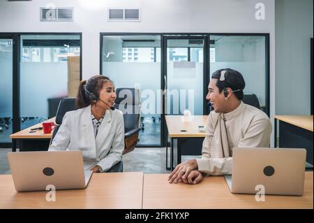Un agent amical de collègue asiatique avec casque et ordinateur portable pour parler bavardage entre le travail dans un centre d'appels Banque D'Images