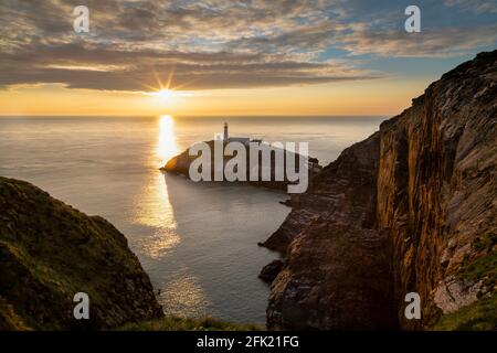 Coucher de soleil sur South Stack Lighthouse construit sur le sommet d'une petite île appelée Ynys Lawd au large de la côte nord-ouest de l'île Sainte, Anglesey, pays de Galles, Royaume-Uni Banque D'Images