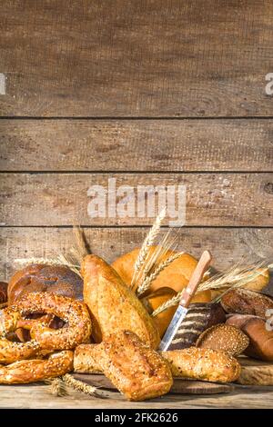 Assortiment de délicieux pains fraîchement sortis du four, sur fond de bois rustique copie espace