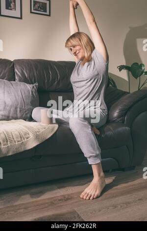 Femme qui se détend les mains, se détend après le travail, souriante femme surjoyeuse assise sur un canapé confortable dans la salle de séjour, appréciant les loisirs paresseux à la maison Banque D'Images