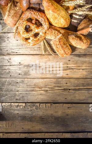 Assortiment de délicieux pains fraîchement sortis du four, sur fond de bois rustique copie espace