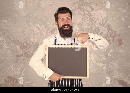 venez ici. présentation du produit. meilleur menu du chef. tableau noir avec espace pour le texte. boulanger professionnel en tablier. joyeux barista avec barbe Banque D'Images