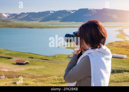 Femme photographe prenant des photos avec son appareil photo professionnel d'un majestc paysage côtier au coucher du soleil Banque D'Images