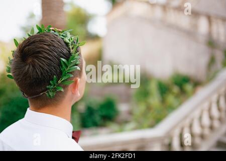 Un homme dans une couronne d'olive dans une chemise blanche sur le fond d'un vieil escalier, vue arrière, gros plan Banque D'Images