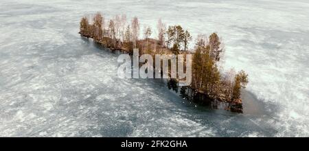 Vue aérienne de dessus petite île au milieu d'une rivière ou d'un lac gelé par glace à Karelia. Banque D'Images