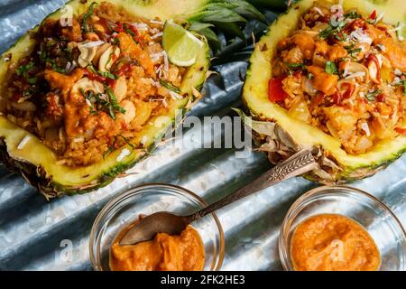 Riz frit au poulet à la noix de cajou thaïlandais servi dans un bol d'ananas avec sriracha et sauce satay aux arachides Banque D'Images