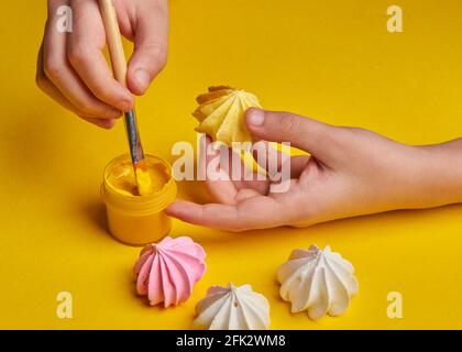 peindre beaucoup de meringues avec une brosse sur un arrière-plan jaune Banque D'Images