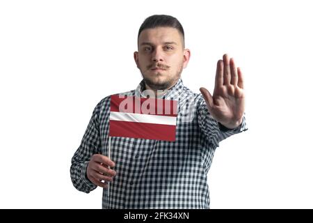 Un homme blanc portant un drapeau de la Lettonie et un visage sérieux montre un panneau d'arrêt de main isolé sur un fond blanc. Banque D'Images