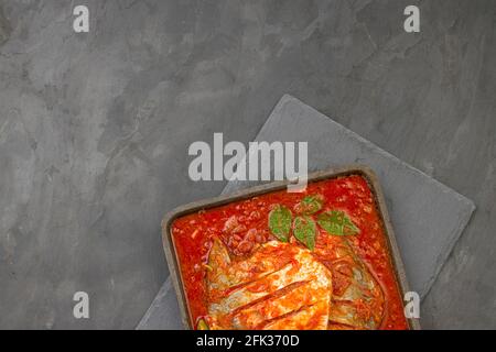 Cari masala blanc pomfret, fait dans le style indien du sud avec une épaisse sauce rouge et garni de piment vert, feuilles de curry et tamarin de malabar Banque D'Images