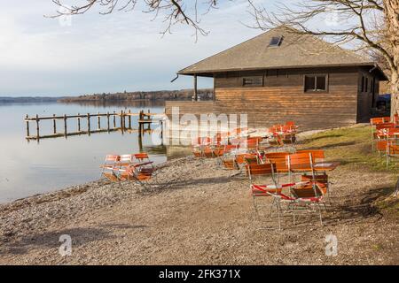 Herrsching, Allemagne - 4 févr. 2021: Chaises et tables sur la promenade au bord du lac de Herrsching am Ammersee, fermée avec ruban barrière. . En raison de Covid Banque D'Images