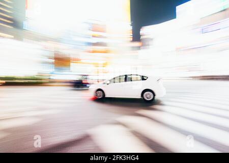 Tokyo, Japon - 13 décembre 2015 : image abstraite d'un prius Toyota blanc au Shibuya Crossing à Tokyo, Japon. Banque D'Images