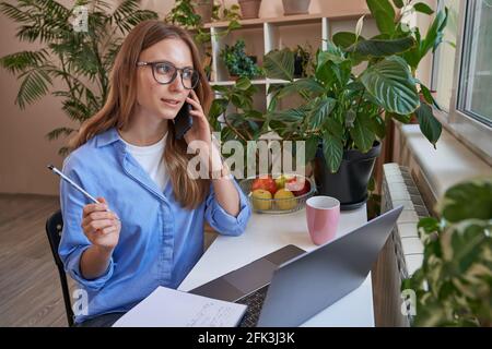 Jeune femme tenant un téléphone portable tout en étant assise à la tableau Banque D'Images