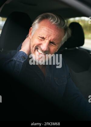 Homme âgé à l'intérieur de la voiture après un accident de la route dans la douleur souffrant de blessure au coup de fouet Banque D'Images