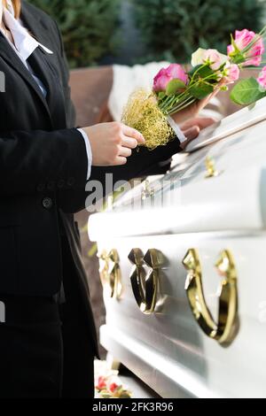 Homme et femme sur deuil funérailles avec rose rose debout à cercueil ou coffin Banque D'Images