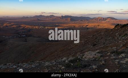 Dernière lumière du soleil tombant dans une vallée du désert modélisant le paysage en contrastes or et violet Banque D'Images