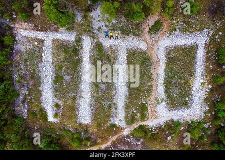 Photo aérienne de l'inscription de Tito à partir de pierres et d'une famille qui s'est posée sur le sol au-dessus de lui au mont Sabiotin, en Slovénie Banque D'Images