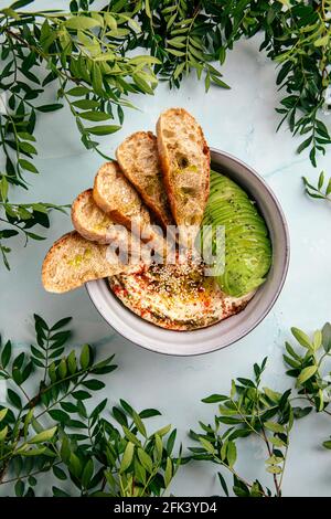 Bol de houmous avec tranches d'avocat et de toasts Banque D'Images