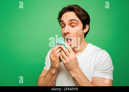 Le jeune homme semble malade et a le nez courant, isolé sur fond vert Banque D'Images