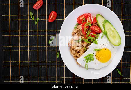 Nasi Goreng. Riz frit au poulet indonésien sur fond sombre. Nasi Goreng est un plat de cuisine indonésien avec du riz, de la viande de poulet, de l'oignon, des oeufs, du végétabl Banque D'Images
