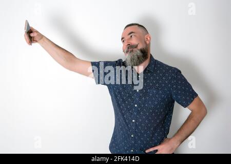 Race blanche gay avec une grande barbe de 40-45 ans, prenant un selfie avec le smartphone Banque D'Images