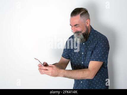 Race de race blanche de 40-45 ans, baissière, regardant son mobile téléphone avec un visage heureux et rire Banque D'Images