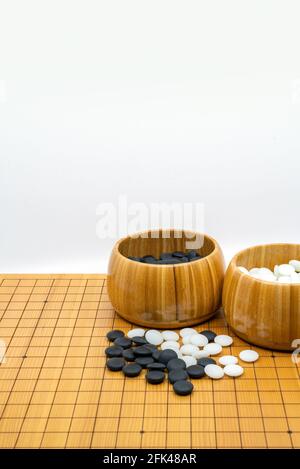 Jeu de société traditionnel isolé de la Chine et du Japon, appelé Go, deux bols en bois ouverts de pierres noires et de pierres blanches. L'image verticale sur b blanc Banque D'Images