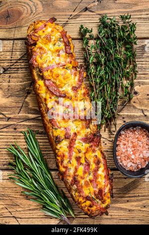 Sandwich pizza sur pain de baguette avec jambon, bacon, légumes et fromage sur table en bois. fond en bois. Vue de dessus Banque D'Images