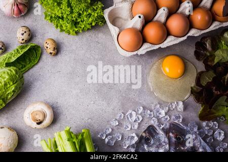 Cadre d'ingrédients de cuisson crus pour des aliments savoureux et sains. dorado frais poisson sur glace, légumes, oeufs sur fond de béton gris vue de dessus. Banque D'Images