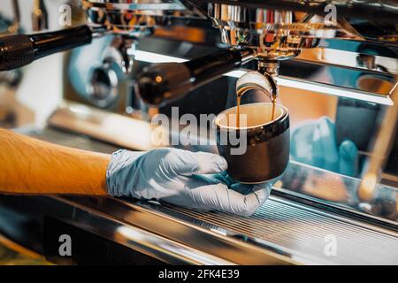 Les mains de l'homme préparent le café, l'espresso frais verse dans une tasse en porcelaine. Cafetière, café-restaurant Banque D'Images