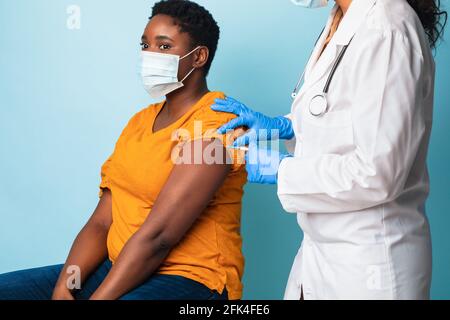 African American Lady in Mask recevant un vaccin antiviral Shot, Studio Banque D'Images