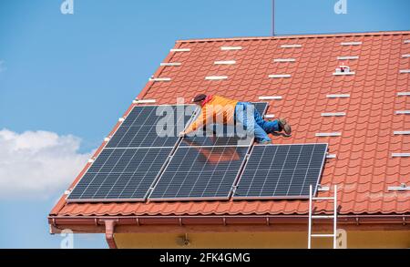 Un travailleur installe des panneaux solaires d'une centrale électrique sur le toit d'une maison privée. Banque D'Images