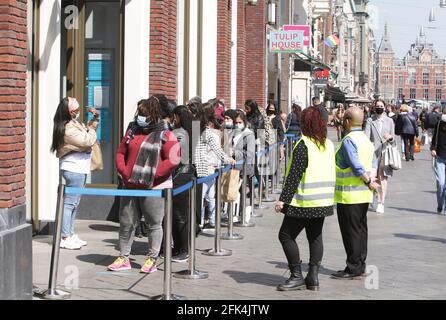 Amsterdam, pays-Bas. 28 avril 2021. Les consommateurs portant un masque facial de protection attendent en file d'attente pour entrer dans un magasin de l'avenue Damrak, dans le centre d'Amsterdam, dans le contexte de la pandémie du coronavirus, le 28 avril 2021 à Amsterdam, aux pays-Bas. Le gouvernement néerlandais prend aujourd'hui un pas important pour relâcher le blocage du coronavirus, après six mois de fermeture des terrasses et des magasins rouvrent mais ferment à 6 h à travers le pays. (Photo de Paulo Amorim/Sipa USA) Credit: SIPA USA/Alay Live News Banque D'Images