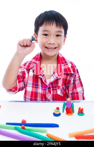 Petit garçon asiatique jouant et créant des jouets à partir de la pâte de jeu. Enfant souriant et montrer ses œuvres de l'argile, sur fond blanc. Renforcer l'imagination Banque D'Images