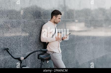 Transport écologique moderne en ville, homme d'affaires avec gadget extérieur et café Banque D'Images