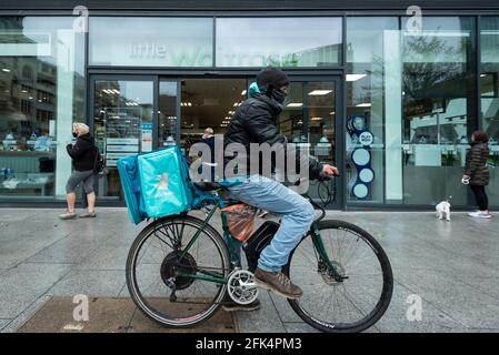 Londres, Royaume-Uni. 28 avril 2021. Un pilote Deliveroo collecte une commande en dehors d'une succursale de Waitrose dans Bankside. Waitrose et Deliveroo ont annoncé un partenariat de deux ans pour des livraisons de maisons rapides qui créera 400 nouveaux emplois à Waitrose pour remplir les commandes devant être collectées par Deliveroo. Le nouvel accord vient après que Waitrose et le épicier en ligne Ocado ont fini de travailler ensemble l'année dernière. Credit: Stephen Chung / Alamy Live News Banque D'Images