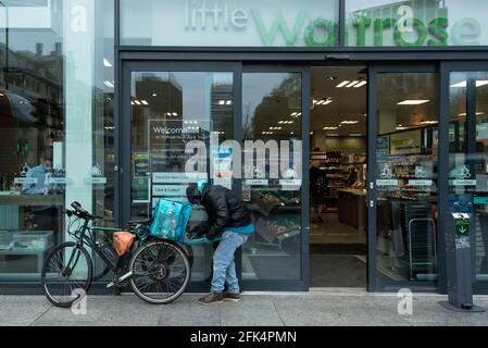 Londres, Royaume-Uni. 28 avril 2021. Un pilote Deliveroo collecte une commande en dehors d'une succursale de Waitrose dans Bankside. Waitrose et Deliveroo ont annoncé un partenariat de deux ans pour des livraisons de maisons rapides qui créera 400 nouveaux emplois à Waitrose pour remplir les commandes devant être collectées par Deliveroo. Le nouvel accord vient après que Waitrose et le épicier en ligne Ocado ont fini de travailler ensemble l'année dernière. Credit: Stephen Chung / Alamy Live News Banque D'Images