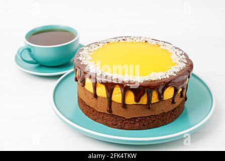 Gâteau au chocolat et à l'orange maison parsemé de tranches d'amande et d'une tasse de thé sur une table en bois blanc. Banque D'Images