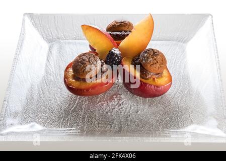 Pêches aux fruits cuites remplies de chocolat et de biscuits amaretti, dessert piémontais typique, Italie, sur une assiette de verre Banque D'Images