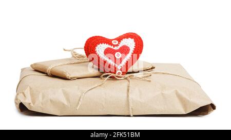 Deux colis de papier kraft attaché avec ficelle et petit coeur rouge fait main isolé sur fond blanc. Un cadeau pour la Saint-Valentin. Banque D'Images