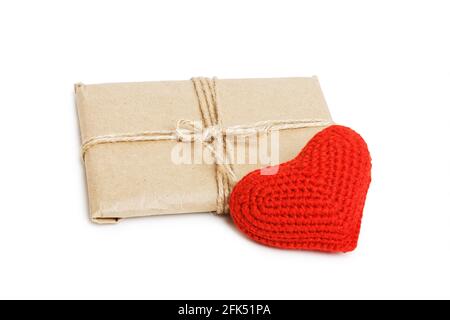 Colis avec papier kraft attaché avec ficelle et petit coeur rouge fait main isolé sur fond blanc. Un cadeau pour la Saint-Valentin. Banque D'Images