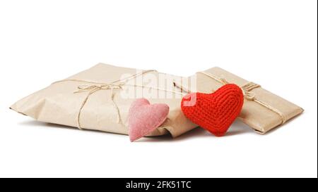 Deux colis de papier kraft attaché avec de la ficelle et de petits coeurs rouges faits à la main isolés sur fond blanc. Un cadeau pour la Saint-Valentin. Banque D'Images