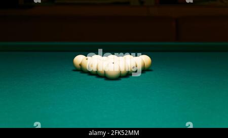 Boules de billard sous forme de triangle sur le feutre vert d'une table de billard sur fond sombre. Mise au point peu profonde. CopySpace. Banque D'Images