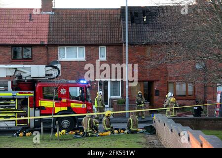 Peggieshill Road, Ayr, Ayrshire, Écosse, Royaume-Uni le feu se brise en maison et s'étend à deux autres propriétés. Pompiers avec appareil respiratoire à l'extérieur de la maison avec trou dans le toit clairement visible Banque D'Images