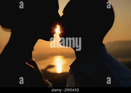 Silhouettes d'un homme et d'une femme embrassant au coucher du soleil sur le fond de la mer, en gros plan Banque D'Images