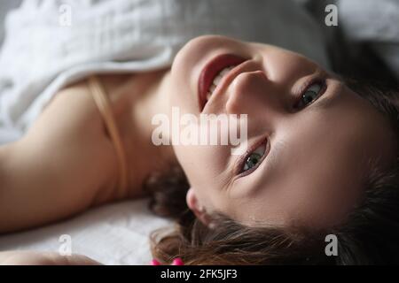 Jeune femme souriante, couchée au lit et regardant vers le haut Banque D'Images