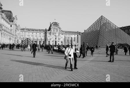 PARIS, FRANCE - 12 MARS 2016 : touristes près de la Pyramide du Louvre au coucher du soleil. Le Louvre est le musée le plus visité au monde. Photo noir et blanc Banque D'Images