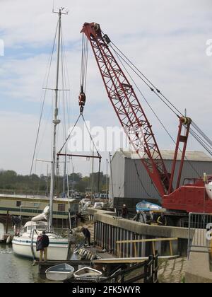 Vue sur une grande grue rouge et des bateaux dans le chantier traditionnel de Melton sur la rivière Deben dans le Suffolk. Banque D'Images