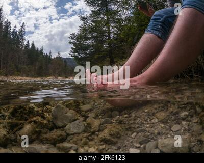 Hiker cooling feet in the cold mountain river Banque D'Images