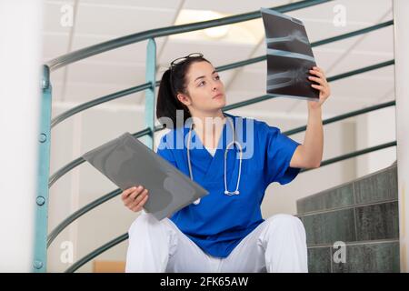 femme médecin assise dans les escaliers regardant les rayons x. Banque D'Images