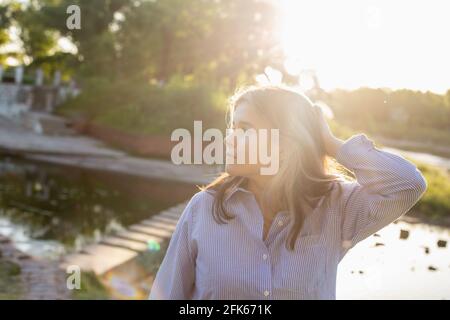 Fille dans les rayons du soleil couchant dans le parc de la ville Banque D'Images